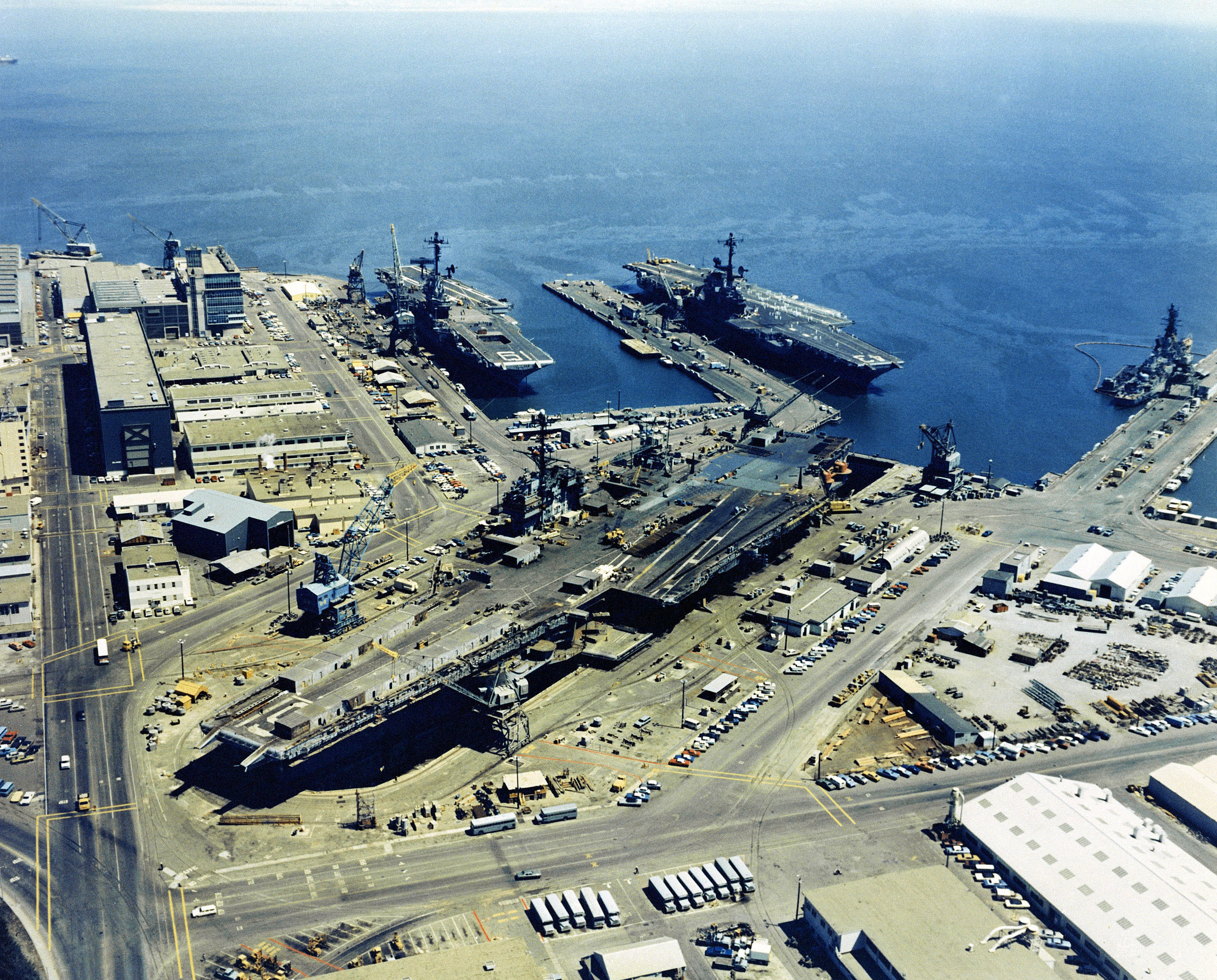 Aerial view of Hunter's Point Naval Shipyard with three docked aircraft carriers.